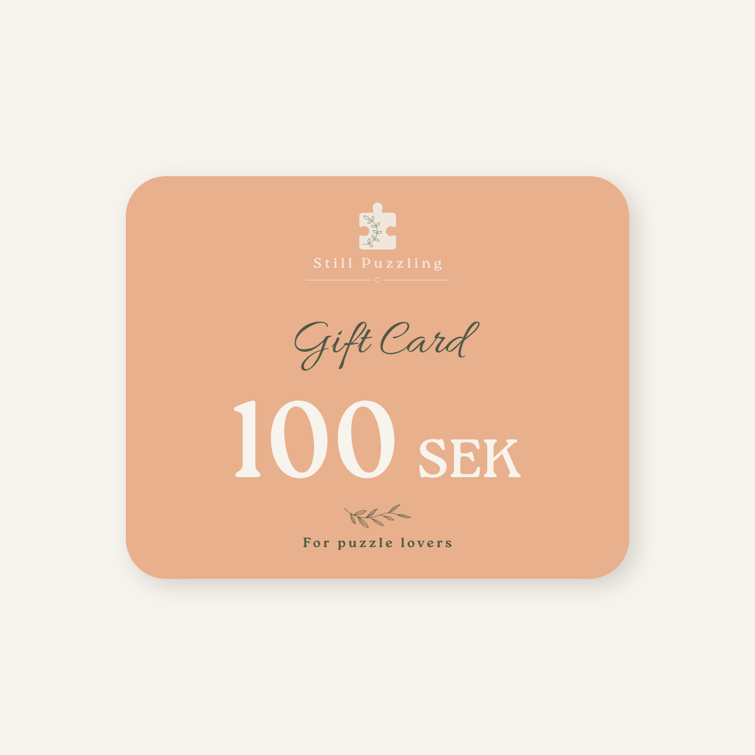 A rectangular gift card with rounded corners in a soft peach color, featuring the text 'Still Puzzling', 'Gift Card', '100 SEK', and 'For puzzle lovers' in white and dark gray lettering, centered on a light cream background.