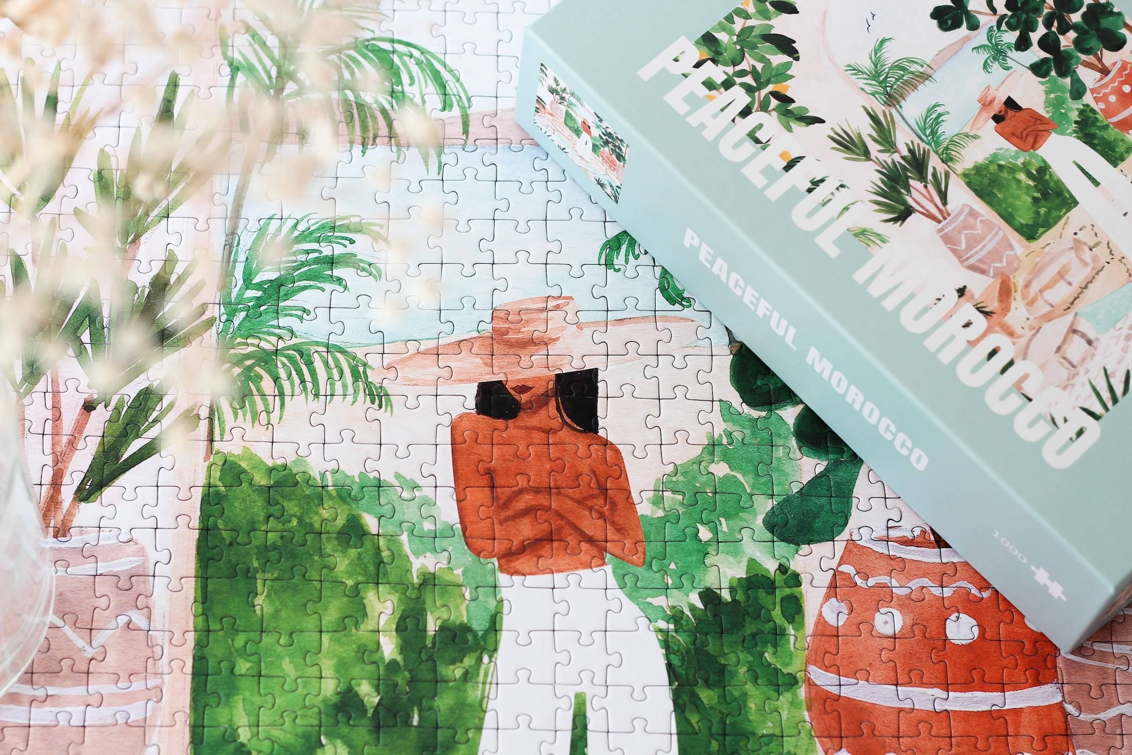 Peaceful Morocco jigsaw puzzle completed section next to a puzzle box showing a woman in a garden.